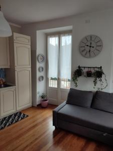 a living room with a couch and a clock on the wall at Regina di Cuori in Andorno Micca