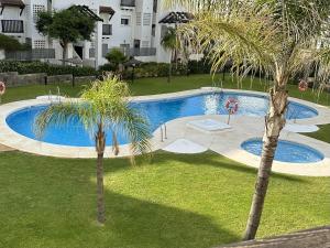 een uitzicht over een zwembad met twee palmbomen bij Ground floor 2bed apartment Duquesa Manilva in San Luis de Sabinillas