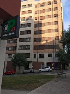 een groot gebouw met auto's geparkeerd voor het bij Acogedor piso céntrico in Lugo