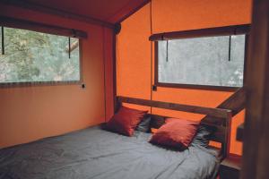 a bed in a room with two windows at Camping Saint-Lambert - Maeva in Millau