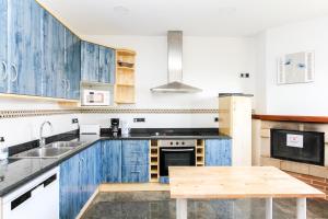une cuisine avec des placards bleus et une table en bois dans l'établissement Villa Serena, à Lloret de Mar