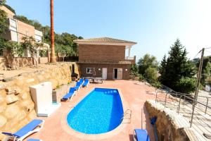 une piscine avec des chaises bleues et une maison dans l'établissement Villa Serena, à Lloret de Mar