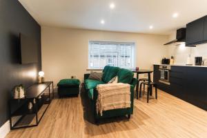 a living room with a green couch and a kitchen at Feature Stone, Stunning Apartment, 2 x King Beds and Single, Sleeps 5 in Castle Cary