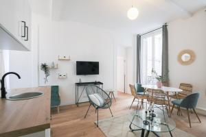 ein weißes Wohnzimmer mit einem Tisch und Stühlen in der Unterkunft Splendide appartement proche Opéra Garnier - 6P in Paris