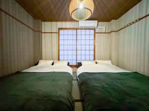 Dos camas en una habitación con ventana. en R 新大阪 FUJI サウナ付きの５LDK　3つのお風呂でグループで楽しめます。, en Osaka