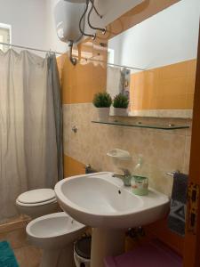 bagno con lavandino, servizi igienici e specchio di CASA VACANZA GALLIPOLI a Matino