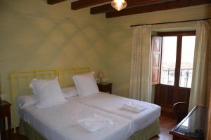 ein Schlafzimmer mit einem Bett mit weißen Laken und einem Fenster in der Unterkunft Casa Rural San Ignacio: una casa indiana en Soria in Valdeavellano de Tera