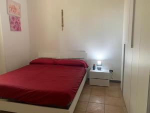 una piccola camera con letto rosso e comodino di CASA VACANZA GALLIPOLI a Matino