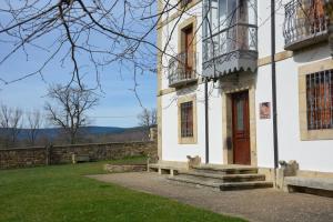 ein weißes Gebäude mit einer Tür und einer Bank in der Unterkunft Casa Rural San Ignacio: una casa indiana en Soria in Valdeavellano de Tera