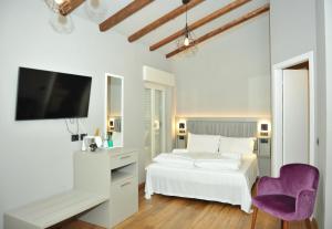 ein weißes Schlafzimmer mit einem weißen Bett und einem lila Stuhl in der Unterkunft Ca’ Bruno Masaneta in Grado