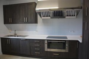 eine Küche mit Holzschränken, Spüle und Mikrowelle in der Unterkunft Casa Rural San Ignacio: una casa indiana en Soria in Valdeavellano de Tera