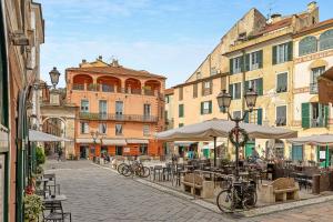una calle de la ciudad con mesas, sillas y edificios en Incantevole casa del Borgo en Finale Ligure