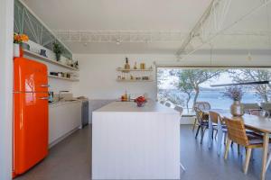 cocina con nevera de color naranja y mesa en A Factoria Beach House by Prishomes en Hio