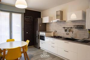 a kitchen with white cabinets and a table with yellow chairs at GoldenSuitesItaly I Trento Suite 1 & Garage Privato in Trento