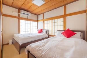 two beds with red pillows in a room with windows at SKY GATEスカイツリー徒歩3分の貸切ヴィラ/成田羽田直通/浅草徒歩15分 in Tokyo