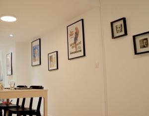 ein Esszimmer mit einem Tisch und gerahmten Bildern an der Wand in der Unterkunft Appartement parisien branché à 10 min de Bastille in Paris