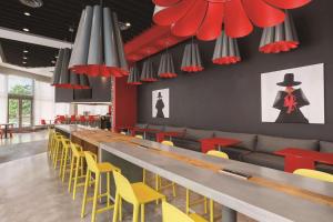 a restaurant with a long bar with yellow and red chairs at Radisson RED Miami Airport in Miami