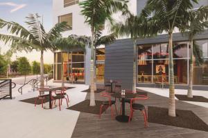a patio with tables and chairs in front of a building at Radisson RED Miami Airport in Miami