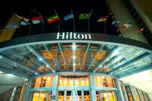 門多薩的住宿－Hilton Mendoza，悬挂旗帜的建筑顶部的希尔森标志