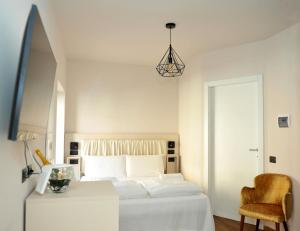 a white bedroom with a bed and a chair at Ca’ Bruno Masaneta in Grado