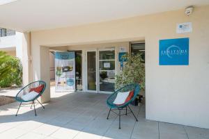 duas cadeiras sentadas em frente a um edifício em Zenitude Hôtel-Résidences - Confort Cannes Mandelieu em Mandelieu-la-Napoule