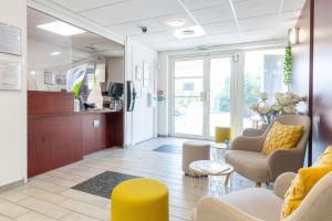 a living room with yellow chairs and a waiting room at Comfort Aparthotel Cannes Mandelieu in Mandelieu-la-Napoule