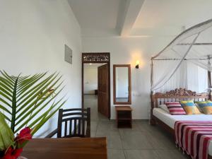 1 dormitorio con cama, mesa y espejo en Swiss Residenz, en Weligama