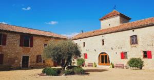 um grande edifício de tijolos com uma árvore em frente em Château de Famille em Créon-dʼArmagnac