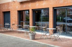 un patio con mesas y sillas frente a un edificio en Clarion Aparthotel Toulouse Blagnac Airport, en Blagnac