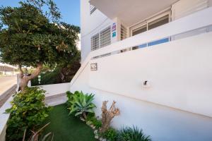 科洛尼亞聖霍爾迪的住宿－Alma Libre Beach Apartment，享有白色房屋和小花园的外部景色