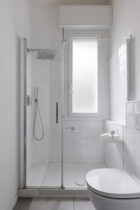 La salle de bains blanche est pourvue d'une douche et de toilettes. dans l'établissement Appartamento Turati 52, à Bologne