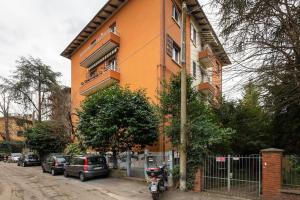 Un bâtiment orange avec des voitures garées devant. dans l'établissement Appartamento Turati 52, à Bologne