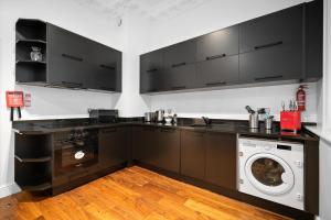 a kitchen with black cabinets and a washing machine at Apartment 1, 48 Bishopsgate by City Living London in London