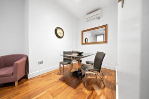 a dining room with a table and chairs and a clock at Apartment 1, 48 Bishopsgate by City Living London in London