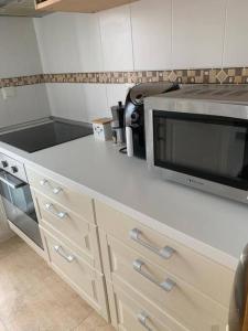 a kitchen with a counter top with a microwave at Ático de 60 m2 en urbanización privada in Noja