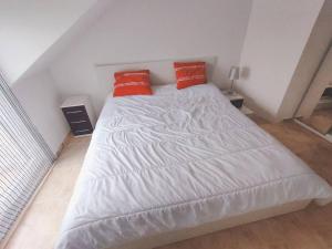 a white bed with two red pillows on it at Ático de 60 m2 en urbanización privada in Noja