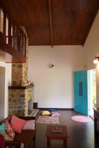 sala de estar con sofá y chimenea en Whispering Waters - Wild Rose Cottage, en Kodaikanal