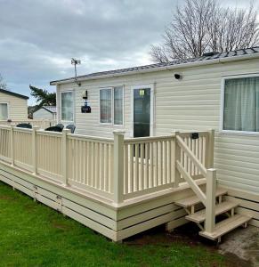 a white mobile home with a wooden deck at Beautiful Static Caravan Hoburne Devon Bay in Paignton