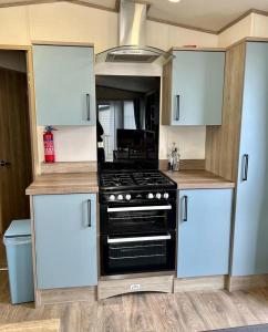 a kitchen with a stove and white cabinets at Beautiful Static Caravan Hoburne Devon Bay in Paignton