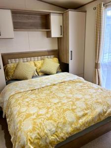 a bedroom with a large bed with a yellow comforter at Beautiful Static Caravan Hoburne Devon Bay in Paignton