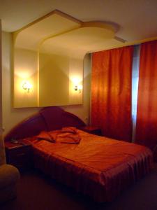 a bedroom with a large bed with a red curtain at Hotel Regat in Piteşti