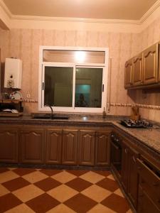 a kitchen with a window and a checkered floor at Family house 2 bedrooms, 2 sdb, near Center of Nador & Airport in Selouane