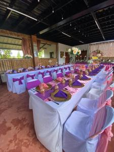 um longo salão de banquetes com mesas brancas e cadeiras roxas em Balay Jardin Murcia 