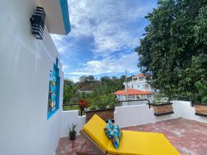 d'un balcon avec un canapé jaune sur un mur blanc. dans l'établissement Casa privada 4 habitaciones aires, piscina billar agua caliente 3 minutos de la playa, à Río San Juan