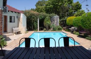 a pool with a table and chairs next to a house at Xaviera Guest House in Pretoria