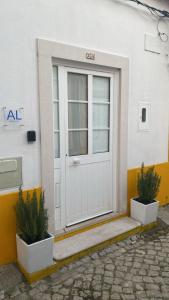 uma porta branca com dois vasos de plantas em frente em Rio D´Sal em Alcochete