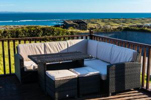 a couch and a table on a balcony with the ocean at Port Aran House in Kilronan