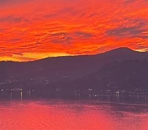 a fiery sunset over the water with wind turbines at Ül Laghèe Blevio Apartments in Blevio