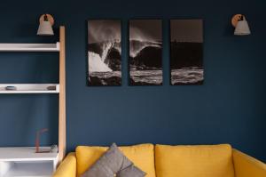 three pictures of a wave on a blue wall with a couch at Port Aran House in Kilronan