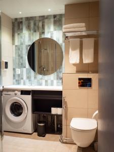 uma casa de banho com uma máquina de lavar roupa e um espelho. em Nallikari Holiday Village - Aalto Seaside Apartments em Oulu